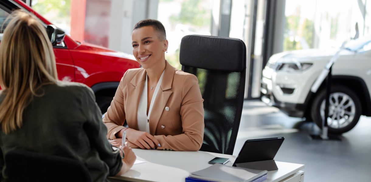 Smiling car rental assistant giving information to customer.