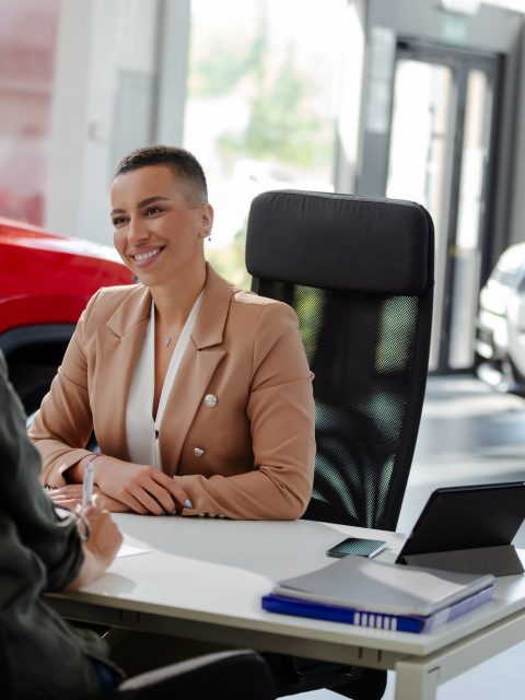 Smiling car rental assistant giving information to customer.