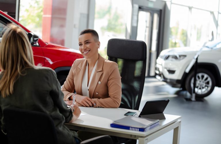 Smiling car rental assistant giving information to customer.